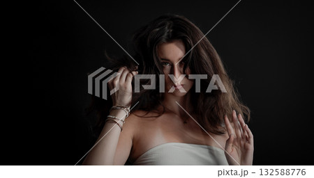 Young woman playing with her long brown hair on black background 132588776