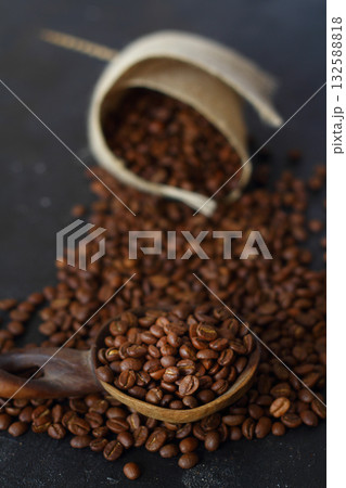 Fresh roasted arabica coffee beans in a wooden spoon and scattered coffee beans on a wooden table. 132588818