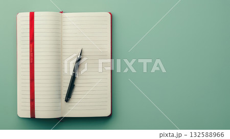 Open lined notebook with pen on green background 132588966