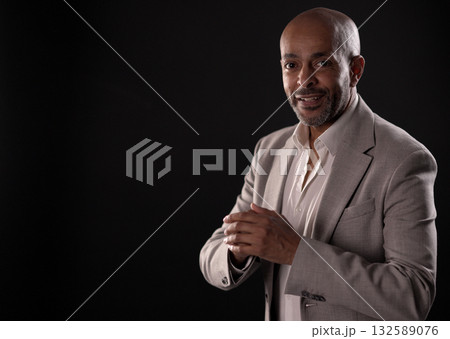 Smiling african american businessman rubbing hands on black background 132589076