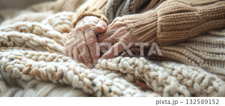Elderly hands resting on cozy knitted blanket warm light comfort care Elderly hands resting on cozy knitted blanket warm light comfort care 132589152