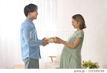 妊婦さんにプレゼントを渡す若いパートナー 妊婦さんにプレゼントを渡す若いパートナー 132589189