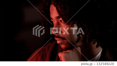 Pensive young man with hand on chin illuminated by red light 132589220