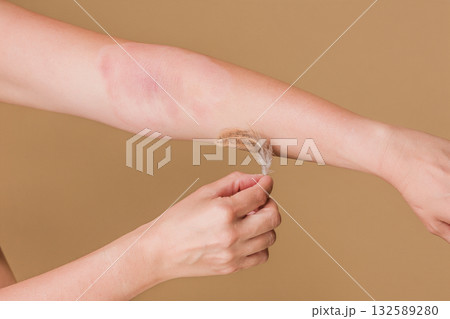 Woman embracing sensitive skin, touching arm with feather Woman embracing sensitive skin, touching arm with feather 132589280