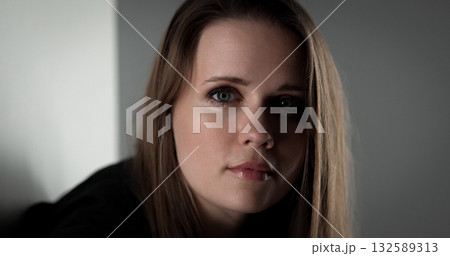 Young woman with long brown hair posing in studio with serious expression 132589313