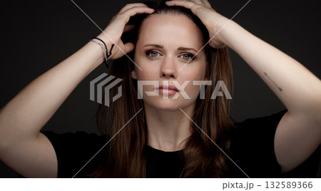 Young woman holding her hair with hands on dark background 132589366