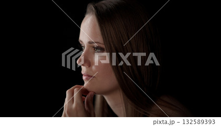 Pensive young woman holding her chin and looking away on black background Pensive young woman holding her chin and looking away on black background 132589393