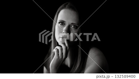 Young woman with finger on lips is thinking on black background 132589400