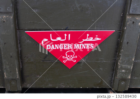 Arabic/English minefield warning red sign - Danger Mines. White skull-and-crossbones on a red. Arabic/English minefield warning red sign - Danger Mines. White skull-and-crossbones on a red. 132589430