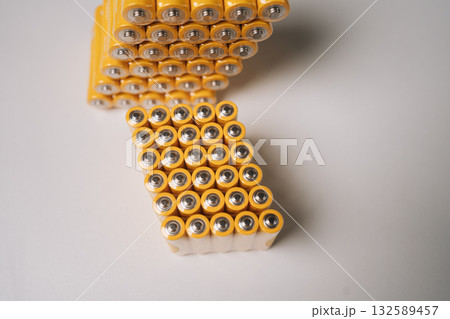 Staggered AAA batteries forming geometric zigzag pattern, positioned precisely across clean white background with subtle shadowing, nobody, no people, close-up. Staggered AAA batteries forming geometric zigzag pattern, positioned precisely across clean white background with subtle shadowing, nobody, no people, close-up. 132589457