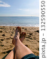 A person's feet are full of sand on the beach with the sea in the background 132590550