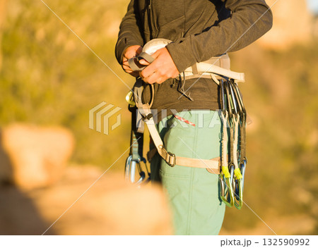A woman looks at a beautiful red rock and takes magnesia in her hand, getting ready for training and climbing. 132590992
