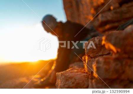 Young girl is preparing for training on the rocks sunset, in the mountains and puts a helmet 132590994