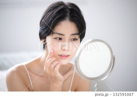鏡を見てスキンケアの悩みを気にする女性のクローズアップ 132591087