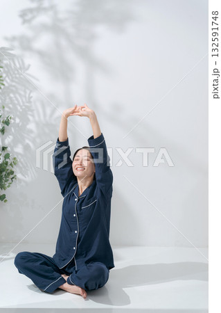 伸びをするパジャマの女性 132591748