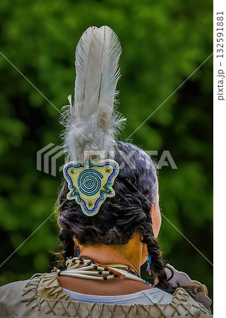 Indigenous hairstyle with feather and bead accessory 132591881