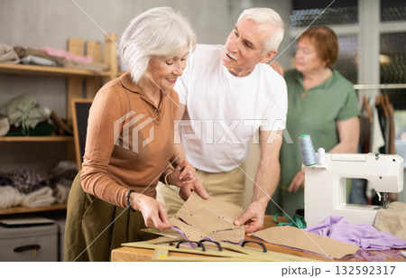 Woman and man discussing patterns with fabric in training sewing workshop Woman and man discussing patterns with fabric in training sewing workshop 132592317
