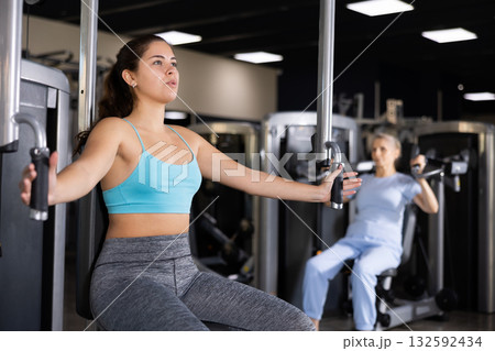 Active young woman training at chest fly machine in gym Active young woman training at chest fly machine in gym 132592434