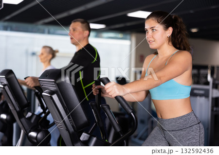 Young girl working out on elliptical machine in gym 132592436