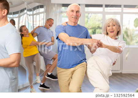 Group of mature men and woman in sportswear learning to dance latin salsa dance in dance class Group of mature men and woman in sportswear learning to dance latin salsa dance in dance class 132592564