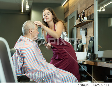 Hairdresser cutting hair of male client. Hairstylist serving client at barber shop Hairdresser cutting hair of male client. Hairstylist serving client at barber shop 132592674