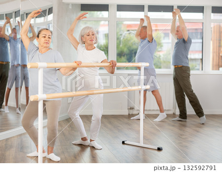 Two mature women practicing plie position during ballet classes Two mature women practicing plie position during ballet classes 132592791