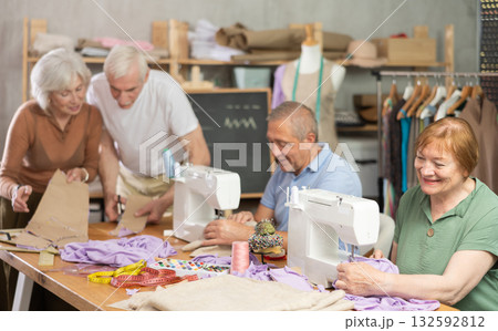 Elderly participants in sewing coterie learn sewing, communicate and talking, sewing, cut fabric by scissors 132592812