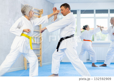 Group of mature people in kimono sparring together in gym during karate training 132592909