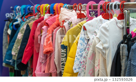 Colorful children's clothes hanging on a rack at a sustainable swap event. Various jackets, sweaters, and shirts in bright colors symbolize reuse, recycling, and eco-friendly fashion for kids. 132593026