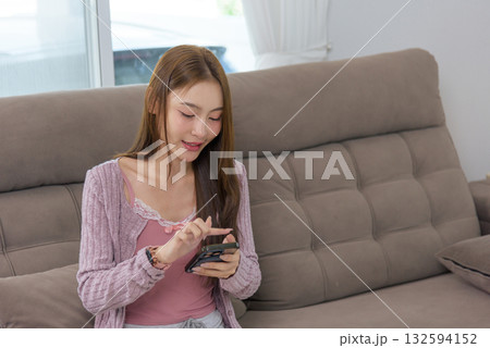 Young woman happy home activity, people enjoy mobile phone interaction, browsing social media, chatting friends, enjoying casual leisure time on cozy couch, feeling contentment 132594152