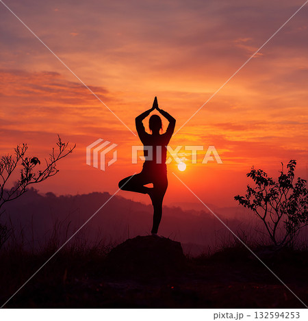 太陽を背に、力強く立つヨギーニ（女性ヨガ実践者）の姿 132594253