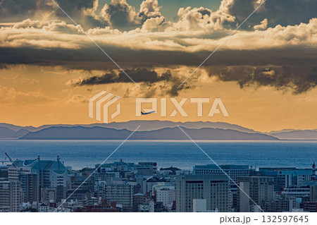 夕焼けの中、那覇空港から飛び立つ旅客機と那覇市街 132597645