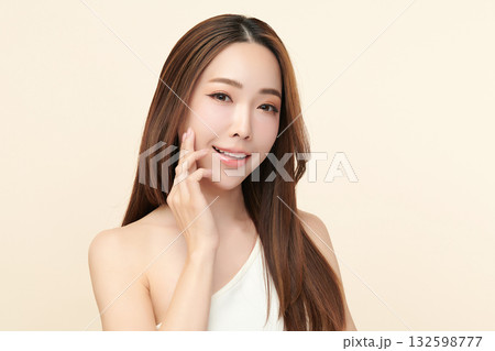 A beautiful young Asian woman with clean, fresh skin against a beige background. Skincare, facial treatment, cosmetology, beauty, and spa. An elegant portrait of an Asian woman. 132598777