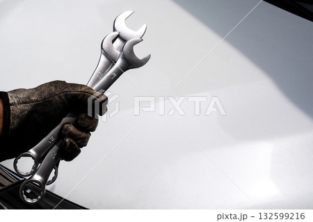 Mechanic hand holding combination wrenches with dirty work gloves, copy space 132599216