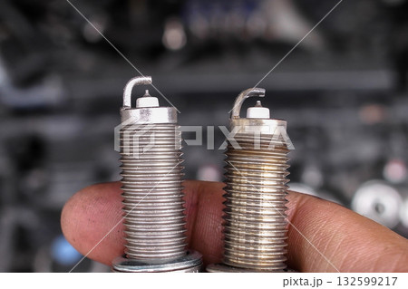 Mechanic hand holding new and used spark plugs side by side Mechanic hand holding new and used spark plugs side by side 132599217