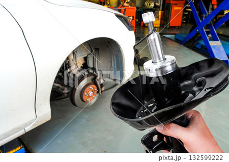Mechanic hand holding new shock absorber in front of car brake system 132599222