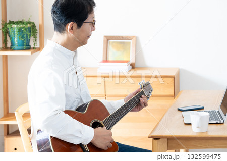 リビングでギターを弾く中年男性 132599475
