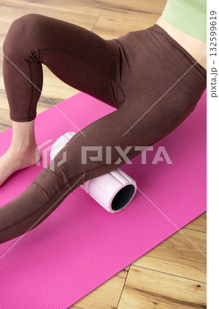 女性が太もものマッサージに使用するフォームローラー 132599619