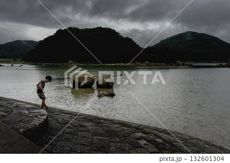 ＜素材＞夕暮れの海辺を散歩する男の子 132601304