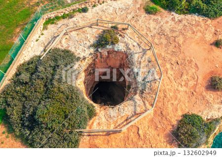 Sinkhole in the ground. Rocky seascape near Praia da Marinha beach in the Algarve region in the Atlantic Ocean, Portugal, Europe Sinkhole in the ground. Rocky seascape near Praia da Marinha beach in the Algarve region in the Atlantic Ocean, Portugal, Europe 132602949