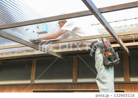 大工さんがポリカ波板をネジで留めている 大工さんがポリカ波板をネジで留めている 132603118