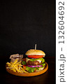 Delicious hamburger with cola and potato fries on a wooden table with a dark brown background behind. Fast food concept. 132604692