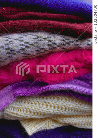 Stack of knitted sweaters. Different knitting patterns. Warm handmade clothes. Knitted sweater cardigans. Craft product concept. Winter fashion. Cozy woven clothing. Knitted fashion. Knitting hobby. 132604730