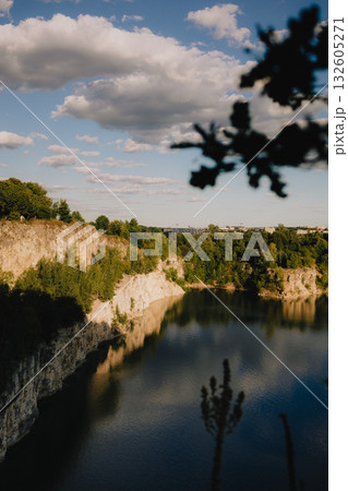 White cliffs reflecting in tranquil waters of Zakrzowek Lagoon at sunset, surrounded by cloudy sky and lush green trees, create serene landscape in Krakow, Poland. Sunset hues in Zakrzowek Lagoon White cliffs reflecting in tranquil waters of Zakrzowek Lagoon at sunset, surrounded by cloudy sky and lush green trees, create serene landscape in Krakow, Poland. Sunset hues in Zakrzowek Lagoon 132605271