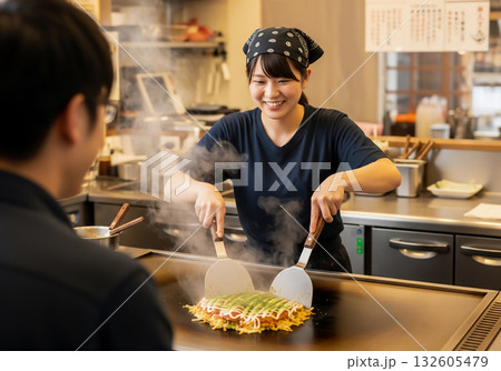 笑顔の女性店員が焼く、湯気立つ絶品お好み焼き 笑顔の女性店員が焼く、湯気立つ絶品お好み焼き 132605479