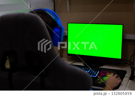 Concept for working long hours at computer at home. Man wearing headphones solves office tasks while working on modern computer remotely from home in cozy atmosphere of his apartment 132605859