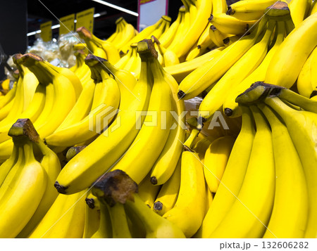 Fresh vibrant yellow bananas piled high in large bunches at a supermarket produce display, representing healthy tropical fruit for consumer grocery shopping 132606282