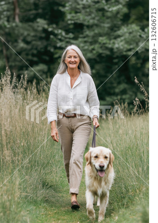 A woman strolls along a path with her fluffy dog A woman strolls along a path with her fluffy dog 132606715