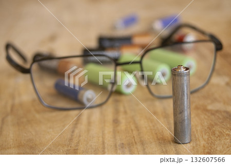 depleted aa battery with eyeglasses on wooden table electronic waste 132607566