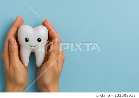 Tooth mascot in caring hands on light blue background symbolizing dental care, hygiene, protection and healthy smile 132608018